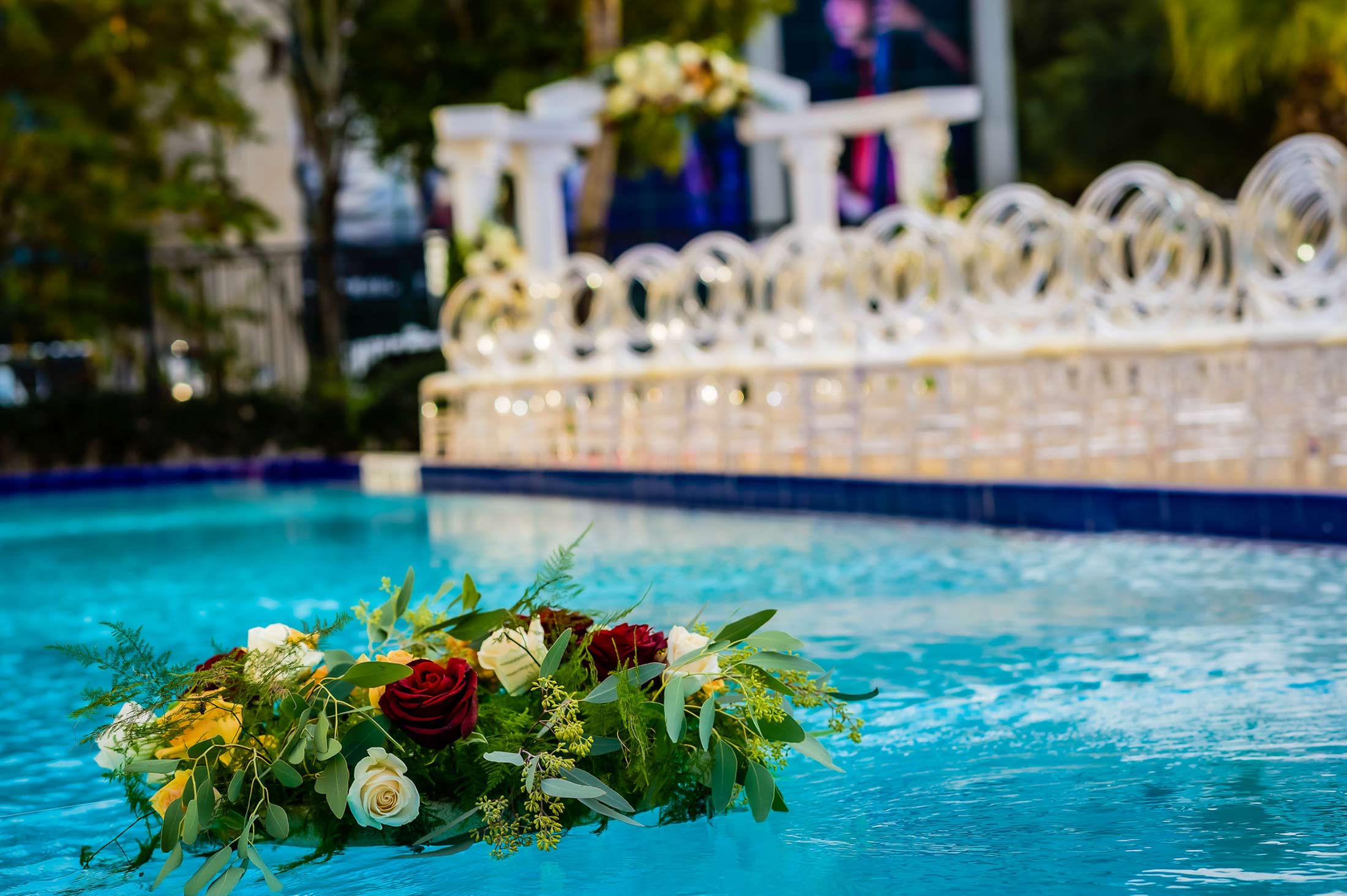 floating flower arrangement in pool with wedding ceremony set up in background