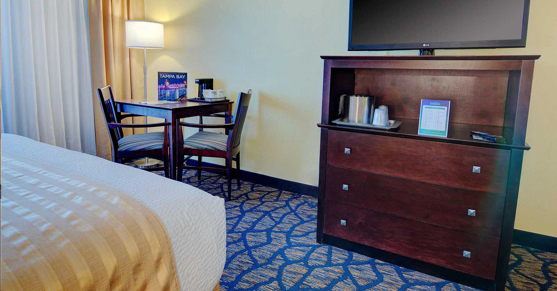 two queen guest room view of tv on dresser, and work desk