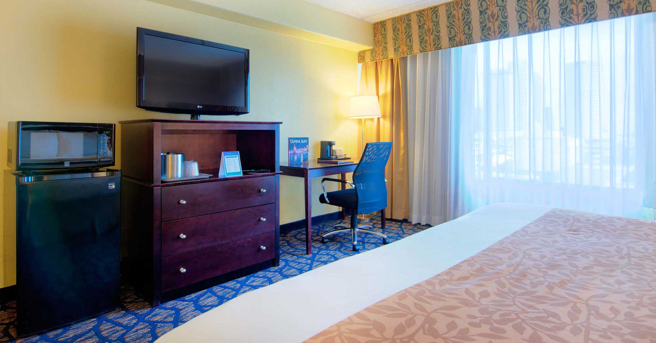 alternate view of one king guest room facing tv on dresser and work desk