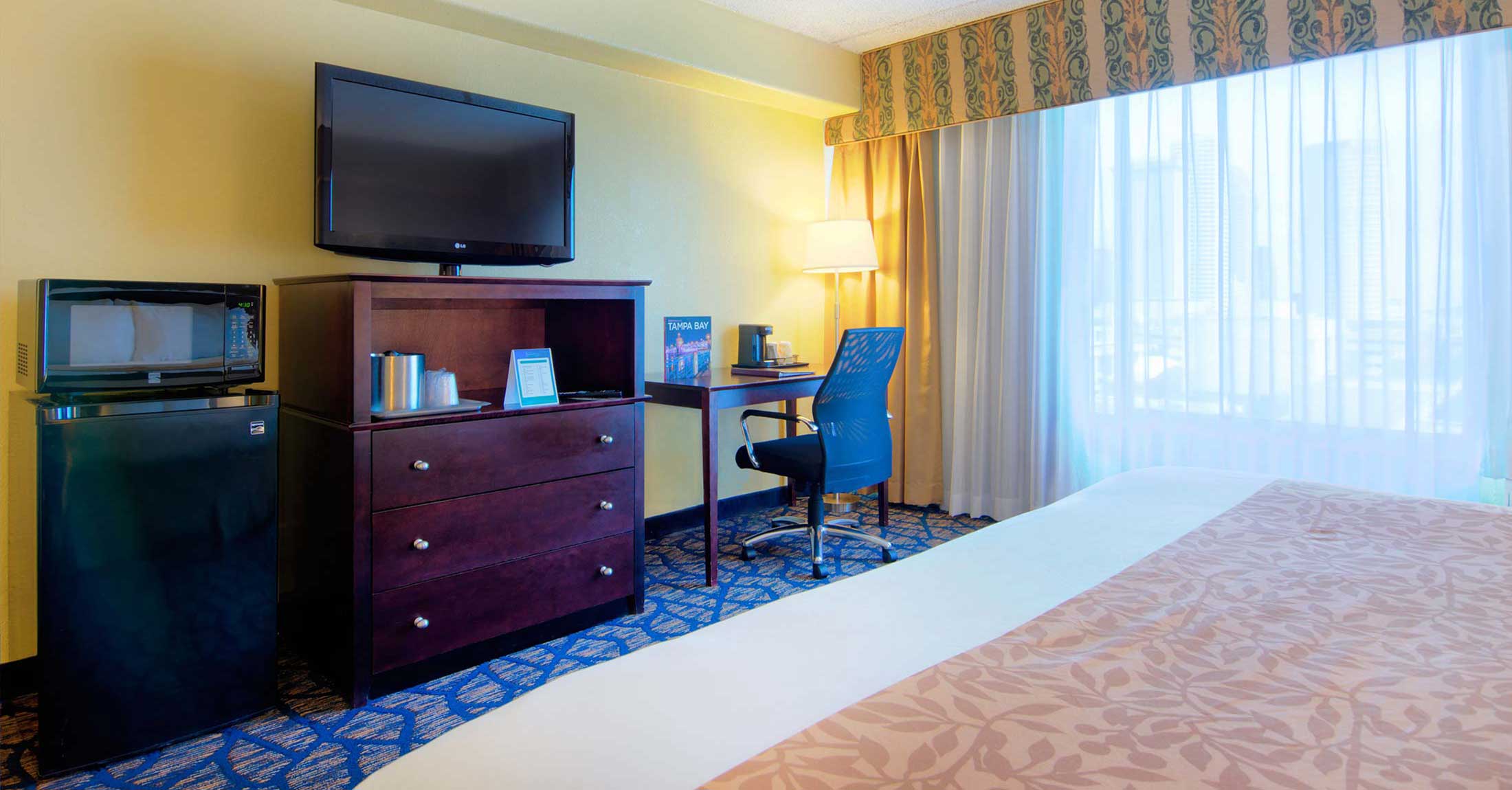 alternate view of one king guest room facing tv on dresser and work desk