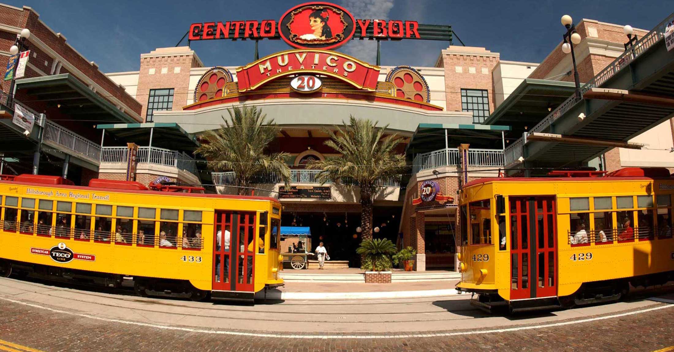 two street cars passing each other underneath the iconic centro ybor sign