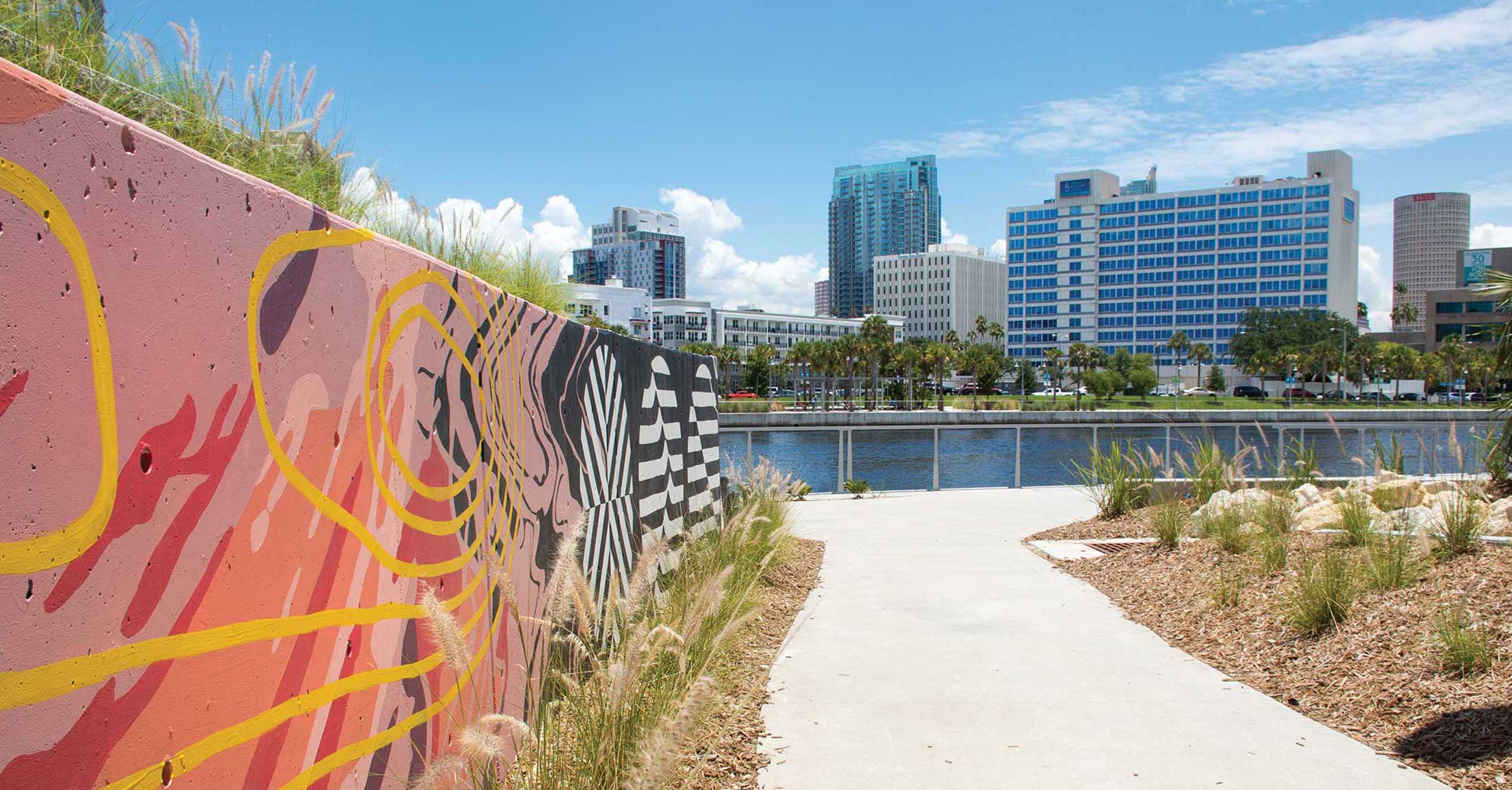 view of hotel from across hillsborough river from tampa river center next to colorful graffiti wall