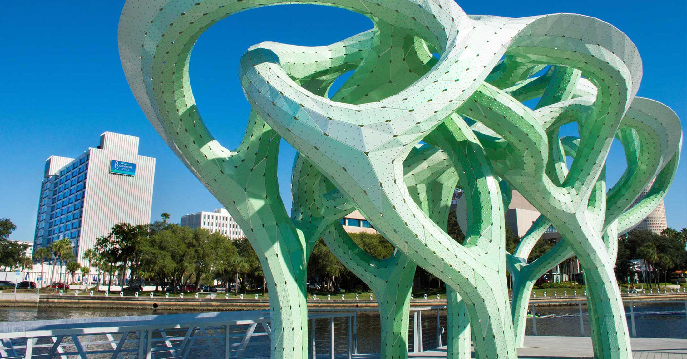 view of hotel from across river next to green public art installation