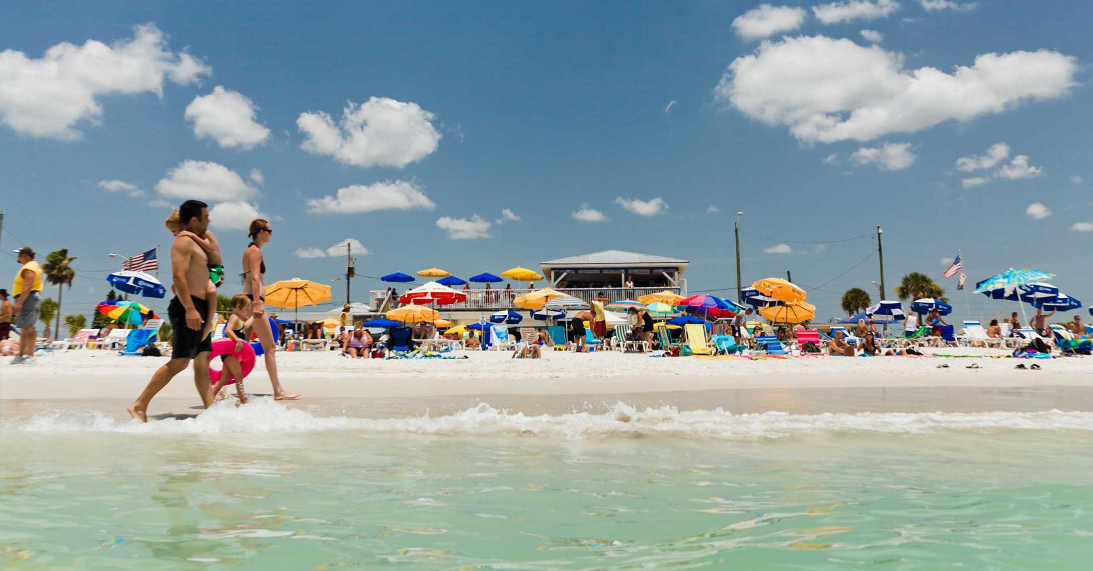 chairs and umbrellas set up on St. Pete Beach, couple walking past on the sand