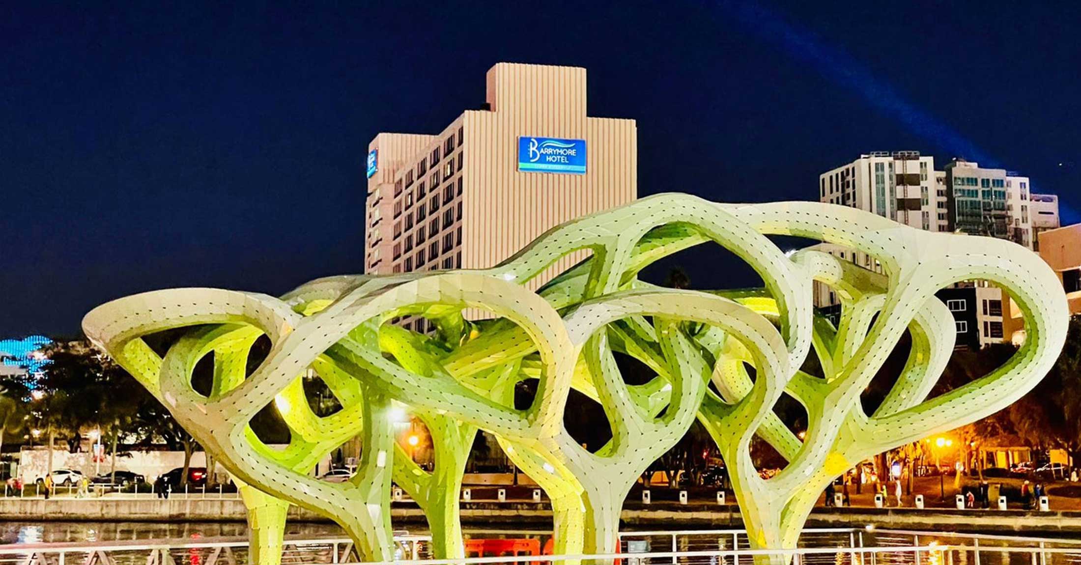 alternate night view of hotel from across river from green public art installation