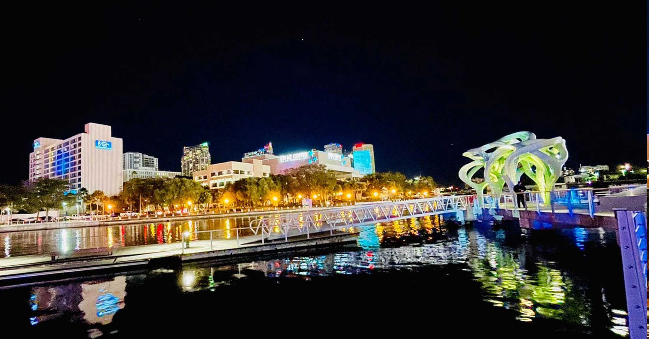 hotel from across the river at night with city lights reflecting off water