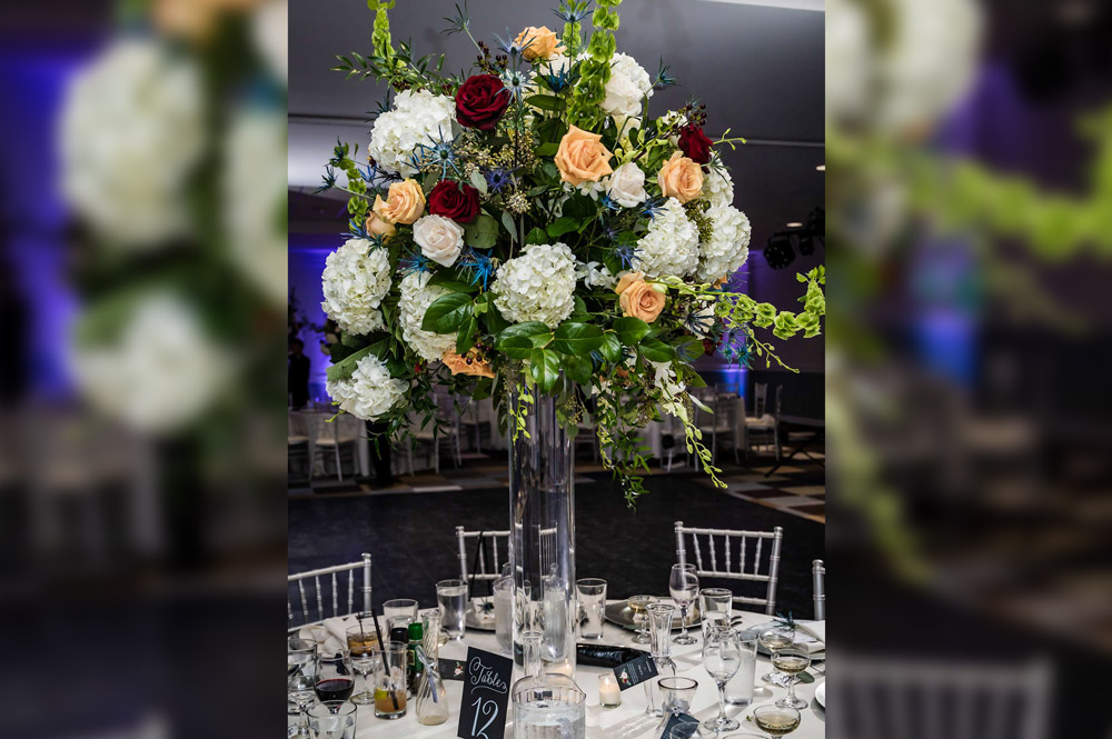 Reception in ballroom, flowers in tall vase, tables decorated for reception