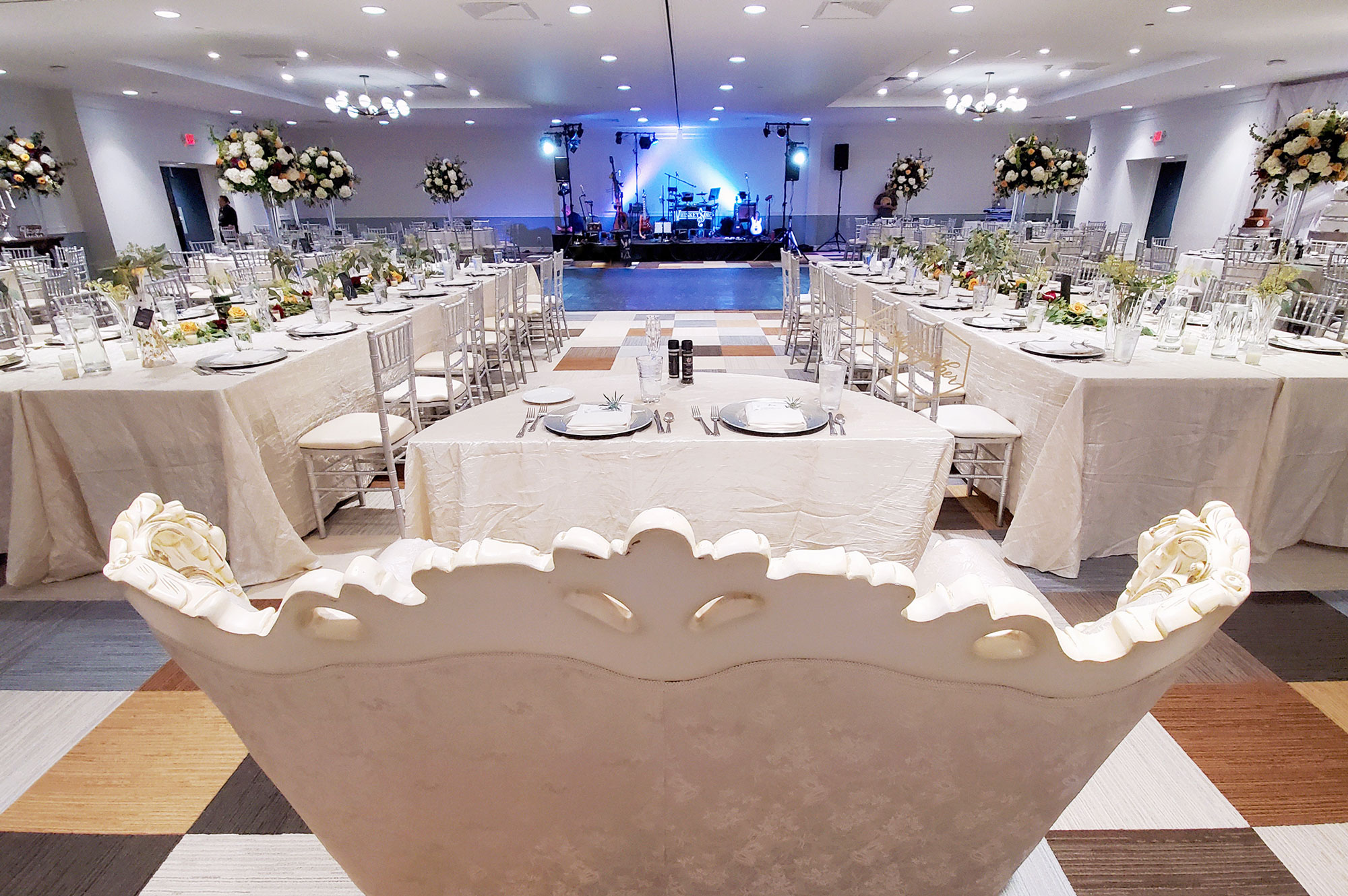 view of wedding reception in ballroom from behind sweetheart table